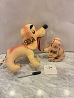Front view of two UCLA felt plush dogs with marker for scale