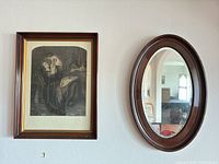 framed print and oval mirror side by side on wall