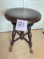 Full view of stool showing seat, legs, brass feet