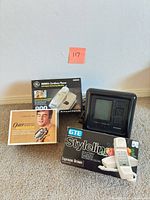 Group shot showing GE cordless phone box, GTE Styleline phone box, Jensen digital clock and Oster booklet