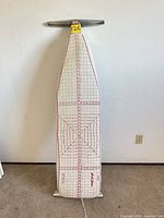 Full view of ironing board standing upright with cover and frame visible