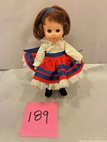 Front view of doll in full outfit standing on card