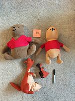 Top view of four plush toys laid on carpet with size reference marker