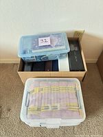 Plastic bin holding 10 Madison light pink yarn skeins and separate containers and binders in box