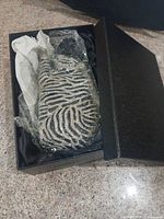 Clutch in original box showing zebra-stripe rhinestone exterior wrapped for protection