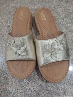 Top view of both sandals showing gold leather uppers and floral appliqué