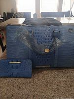 Front view of blue croc-embossed weekender bag with matching wallet
