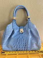Front view of light blue croc-embossed Brahmin satchel with ruler for scale