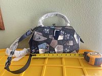 Front view showing patchwork design, strap, clasp, tape measure width