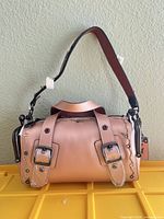 Front view showing metallic leather body, twin buckle straps, protective film