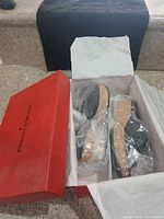 Open Donald J Pliner shoe box showing both black cork-soled wedge sandals wrapped in plastic