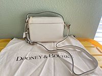 Front view of ivory leather crossbody bag on dust bag