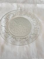 Clear pressed crystal dinner plate with floral leaf embossed pattern visible on rim and center