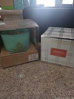 Front view showing boxed teal Hanna's candle and boxed HomeWorx candle