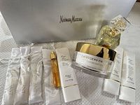 Group shot showing perfume bottle, body cream jar, travel spray, four boxed sample vials, satin pouches and Neiman Marcus gift box