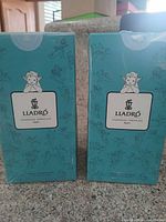 Two factory-sealed Lladró turquoise boxes, one likely containing candle jar, the other porcelain lid