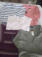 All five tops laid out showing variety and tags