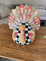 Front view of ceramic Mackenzie-Childs turkey figurine showing checked body and multicolor tail