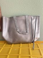Front view of silver metallic tote with handles and zipper detail