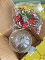 Ornament inside box with packaged ribbon topper