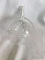 Full view of clear crystal ornament showing etched bells, ribbon and floral motif