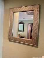 Front view of ornate rectangular metal wall mirror mounted on wall