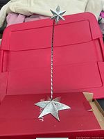 Full view of silver metal ornament stand assembled upright on red surface