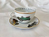 Cup on saucer showing car graphics and gold trim