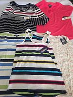 Five women’s tops laid out showing variety and tags