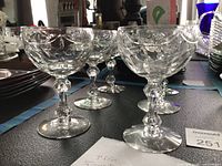 Side view of six matching cut crystal coupe glasses showing dogbone air-trapped stems and cut bowl pattern