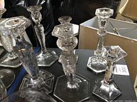 Group of six glass candlesticks showing varying designs and clear glass detail