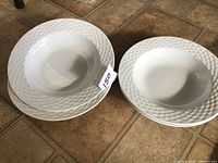 Four white basket weave pasta bowls stacked and side view