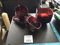 Stacked ruby red square bowls, four cups and three saucers arranged on surface