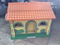 Front exterior of yellow plastic Dora house with orange roof and floral decals