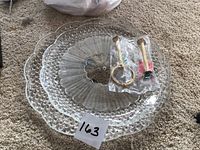 Top view of larger scalloped glass plate with hardware bags on top and lot number card
