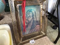 Front view of framed lenticular print showing Jesus portrait inside gold lattice frame with red ribbon