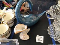 Overall view of blue Jaru swan next to white speckled Haeger candle holder