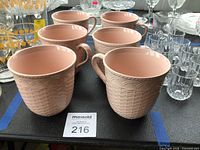 Six pink basket-weave Mikasa mugs grouped on table