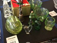 Overview showing silver bell in box, green bowls, miniature steins, uranium glass pieces and alpaca figurine