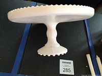 Top view of pink milk glass cake stand showing scalloped hobnail rim and plate surface
