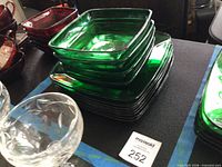 Stack of green square glass bowls atop plates