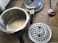 Pressure cooker pot, lid, steamer insert laid out on floor