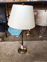 Full view of brass stick lamp with shade on carpeted floor