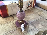 Overall view of amethyst glass lamp showing glass body, wood base, brass socket and frayed cloth cord