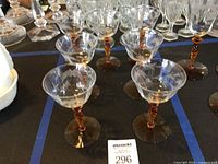 Nine coupe glasses with amber stems arranged on table