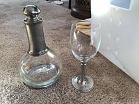 Decanter standing beside one wine glass on carpet