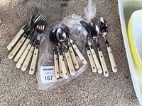 Group shot showing all 18 pieces—forks, large spoons, small spoons—off-white handles visible