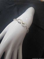 Bracelet displayed on hand form showing infinity symbol and chain