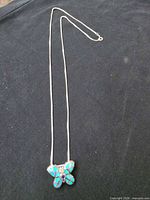 Full view of sterling silver necklace laid flat showing chain and butterfly pendant
