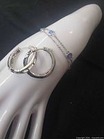 Hoop earrings and bracelet displayed on mannequin hand